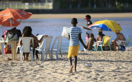 lauro de freitas, bahia / brazil - january 16, 2017: Teenager is seen working with cheese seller on Buraquinho Beach in the city Lauro de Freitas, which characterizes child labor.