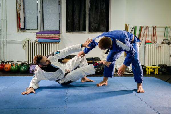 Brazilian Jiu Jitsu BJJ martial arts training sparring at the academy two fighters in technical stand up guard position drilling techniques practicing in a gi kimono self defense