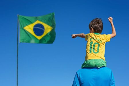 a child on father is pointing to flag of brazil 